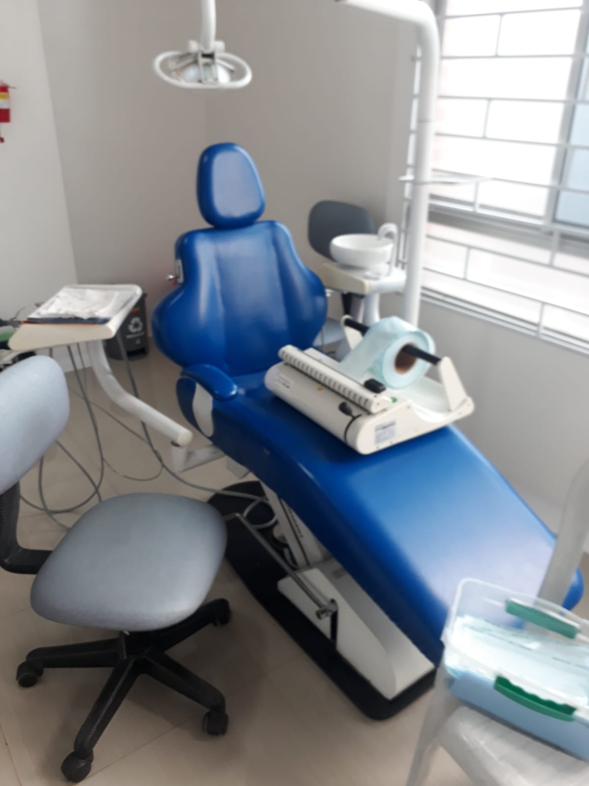 Unidad odontológica completa con sillón eléctrico azul, lámpara de fotopolimerización y escupidera instalada en consultorio dental